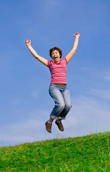 Young happy woman jumping high against b
