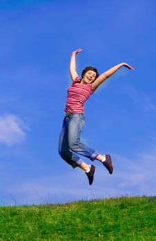 Young happy woman jumping high against b