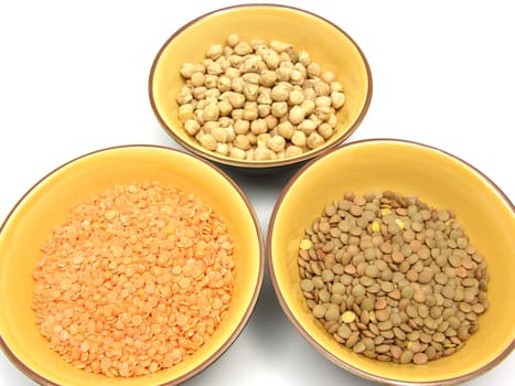 Three ceramic bowls with chickpeas,red and plate lentils