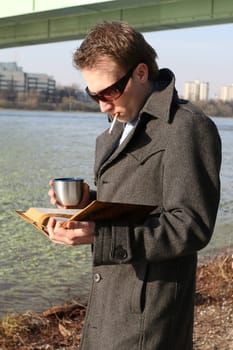 Man reading and smoking on riverbank