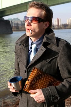 Man smoking and drinking tea outdoors