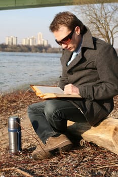 Man reading book on the shore