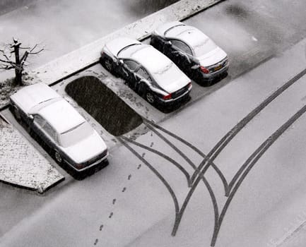 Snowy cars and tracks in freshly fallen snow in a parking lot