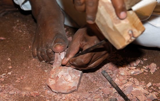 Stonemason from India at work,stone block is held with foot,indi