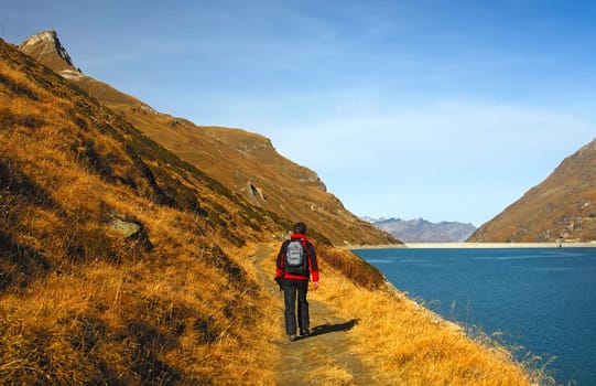 Hiker on an autumn hike on the banks of a dam in the mountains
