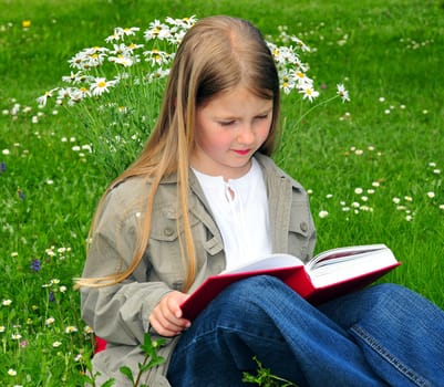 Child reading book on meadow