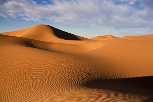 desert sand dunes with cloudy blue sky