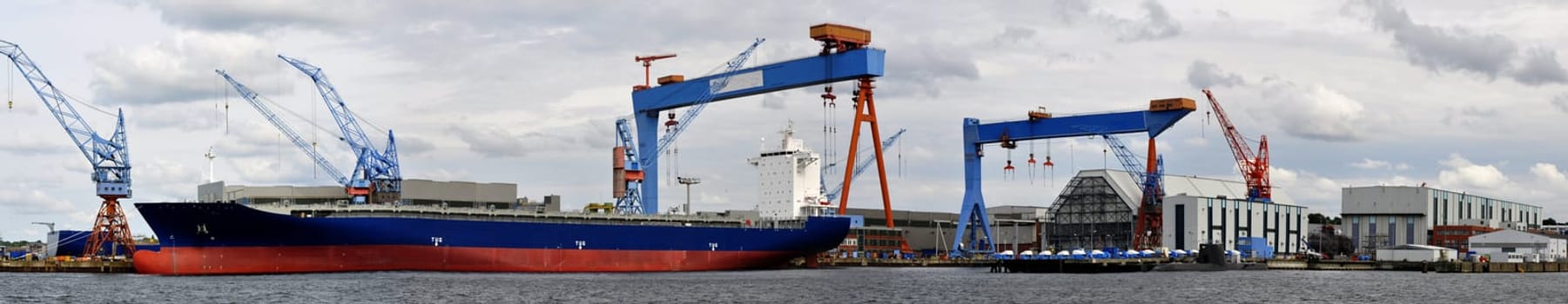 a panoramic shot of the Kiel shipyard with a cargo ship in front of it