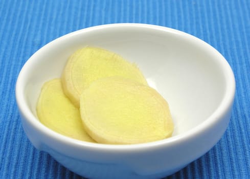 Ginger in porcelain bowl against blue background