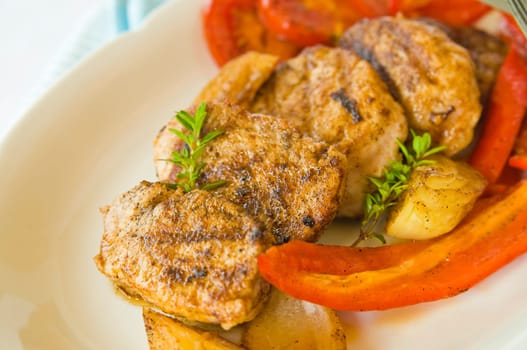 Pork medallions with fried onions,bell pepper and tomatoes on plate anger