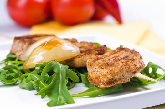 Pork medallions on a skewer with onions on rocket salad