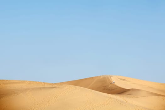 two people walking in desert dunes