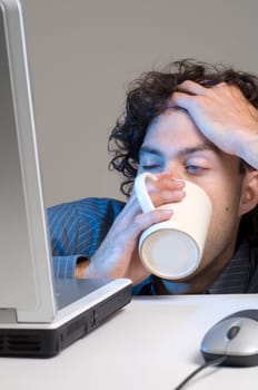 tired man at computer desk with coffee
