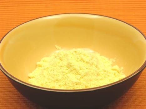 Cornmeal in a ceramic bowl on orange background
