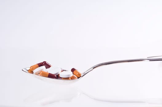 Various tablets in spoon on white background
