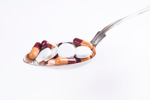 Various tablets in spoon on white background
