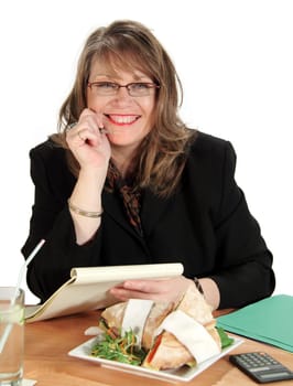 Middle aged businesswoman works at her desk about to have lunch.