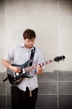 man playing guitar against wall