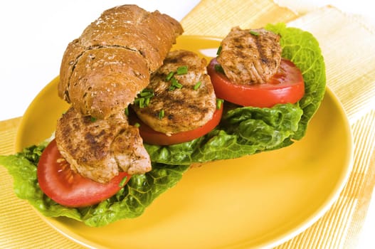 wholemeal sandwich with pork fillet,lettuce,tomatoes and bell pepper on a yellow plate