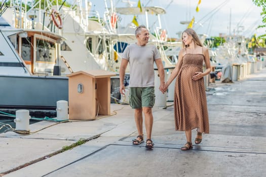 A happy, mature couple over 40, enjoying a leisurely walk on the waterfront, their joy evident as they embrace the journey of pregnancy later in life.