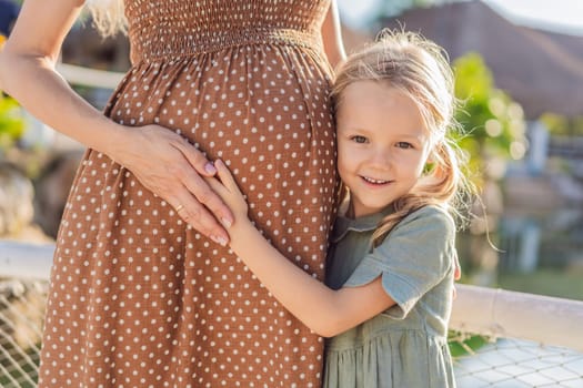 A heartwarming moment captured as a daughter lovingly embraces her mother's pregnant belly, sharing in the excitement and anticipation of a new family member.