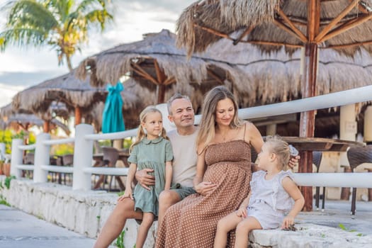 A happy, mature couple over 40 with their two daughters, enjoying a leisurely walk in a park, their joy evident as they embrace the journey of pregnancy later in life.