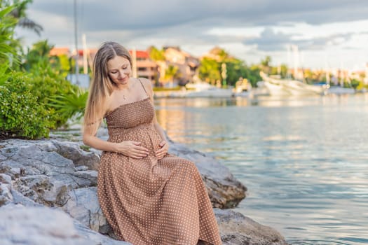 Pregnant woman hugging her tummy standing outdoors surrounded by nature. Pregnancy, expectation, motherhood concept.