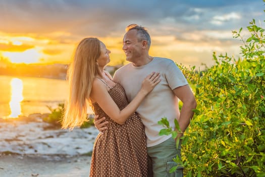 A happy, mature couple over 40, enjoying a leisurely walk on the waterfront On the Sunset, their joy evident as they embrace the journey of pregnancy later in life.