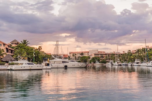 Luxury yachts docked in sea port at colorful sunset. Marine parking of modern motor boats.