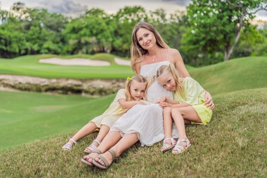 A happy family, two girls, dad, and a pregnant mom, enjoys quality time together on a lush green lawn, creating cherished memories of togetherness.