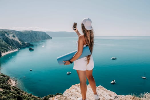 Young woman with black hair, fitness instructor in pink sports leggings and tops, doing pilates on yoga mat with magic pilates ring by the sea on the beach. Female fitness daily yoga concept