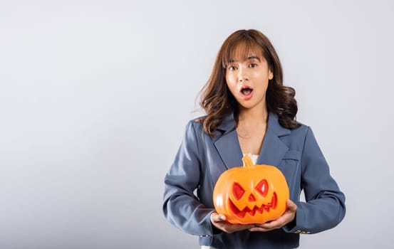 Asian woman holding an orange pumpkin with a joyful demeanor, immersed in the enchanting presence of ghost pumpkins, perfect for Halloween-themed content. Halloween Day Concept