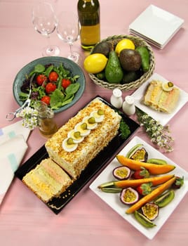 Layered salmon, avocado and curried egg loaf with a fruit platter and salad.