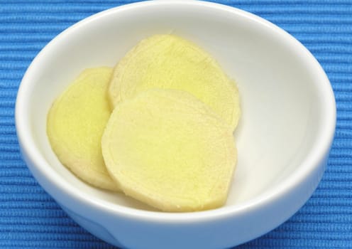 Ginger in porcelain bowl against blue background