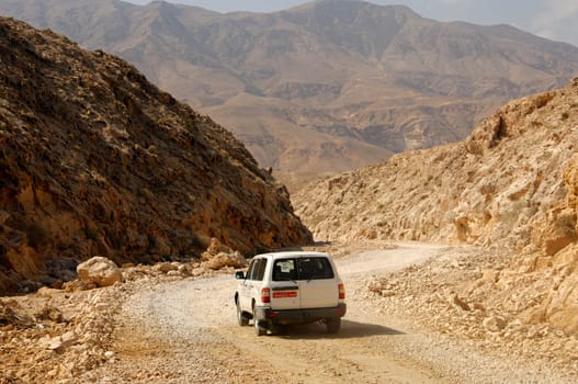 Jeep on a dusty gravel road in a dry wadi,Sultanate of Oman