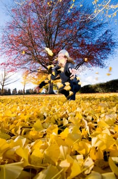 Women throwing yellow autumn leaves