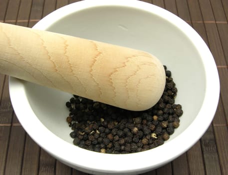 Peppercorns in porcelain bowl with mortar
