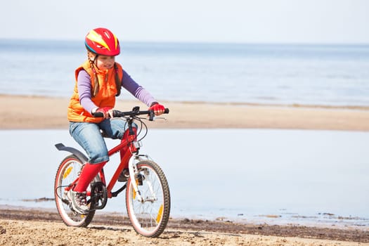 Girl riding on bicycle along beach