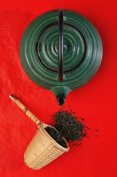 Chinese teapot and a wicker scoop with herb tea leaves