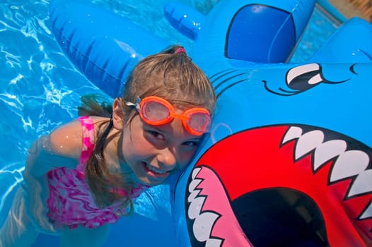 Girl playing in swimming pool with inflatable shark