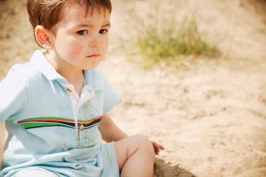 Little boy sitting on the sand