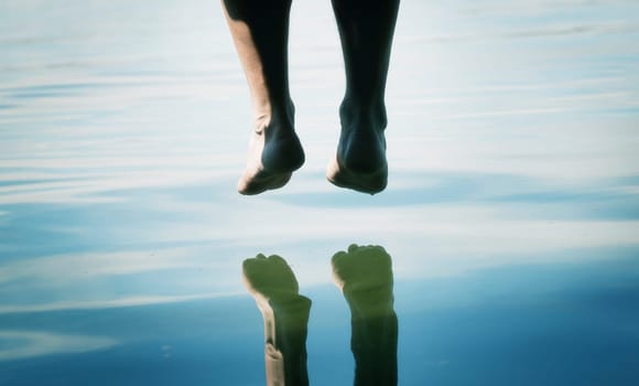 A pair of feet dangling over the water