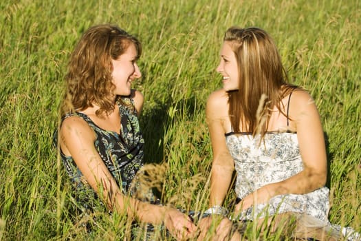 Two women sitting in field talking