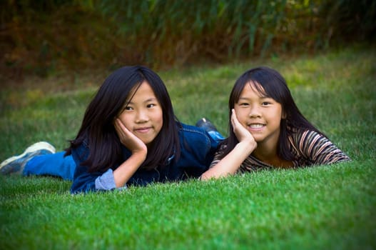Two sisters lying in the grass