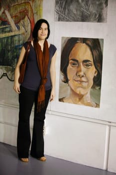 Woman standing in front of her likeness in an art gallery