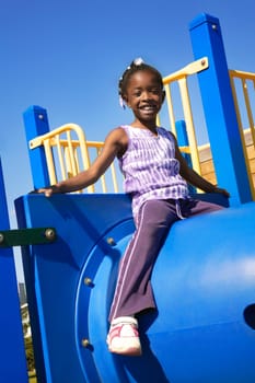 Little girl sitting atop playground equipment