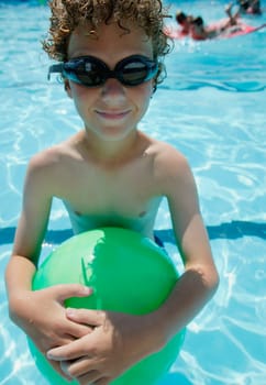 Boy holds ball in pool