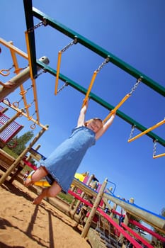 Child swinging on Monkey bars at playground