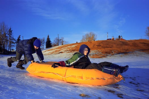 Two boys push a raft down a hill