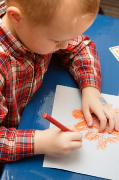 Little boy in kindergarten drawing a Halloween picture in his class